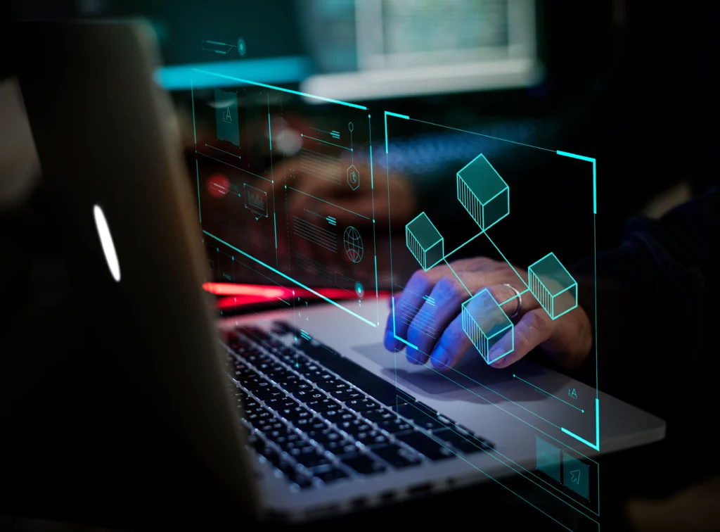 Imagen de unas manos trabajando en una laptop negra, alrededor de las manos hay iconos tecnológicos flotantes en color azul neón.